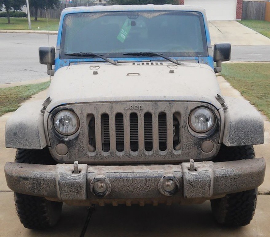 A 2015 Jeep Wrangler Willys Wheeler Edition covered in dried muddy water